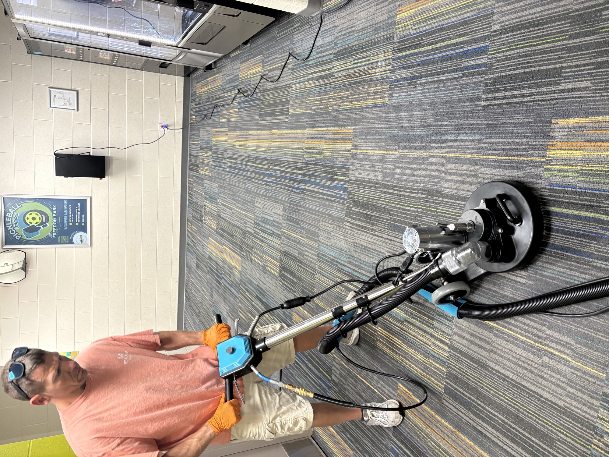 Technician using a rotary extraction tool on commercial carpet